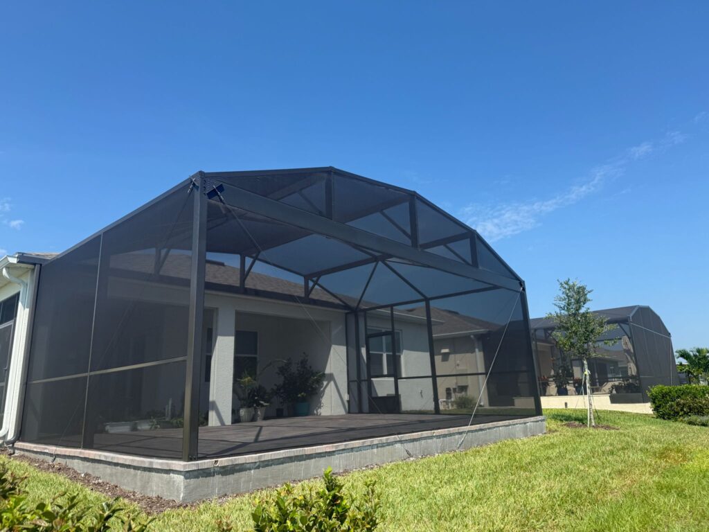 Large black aluminum screen enclosure attached to single-story home