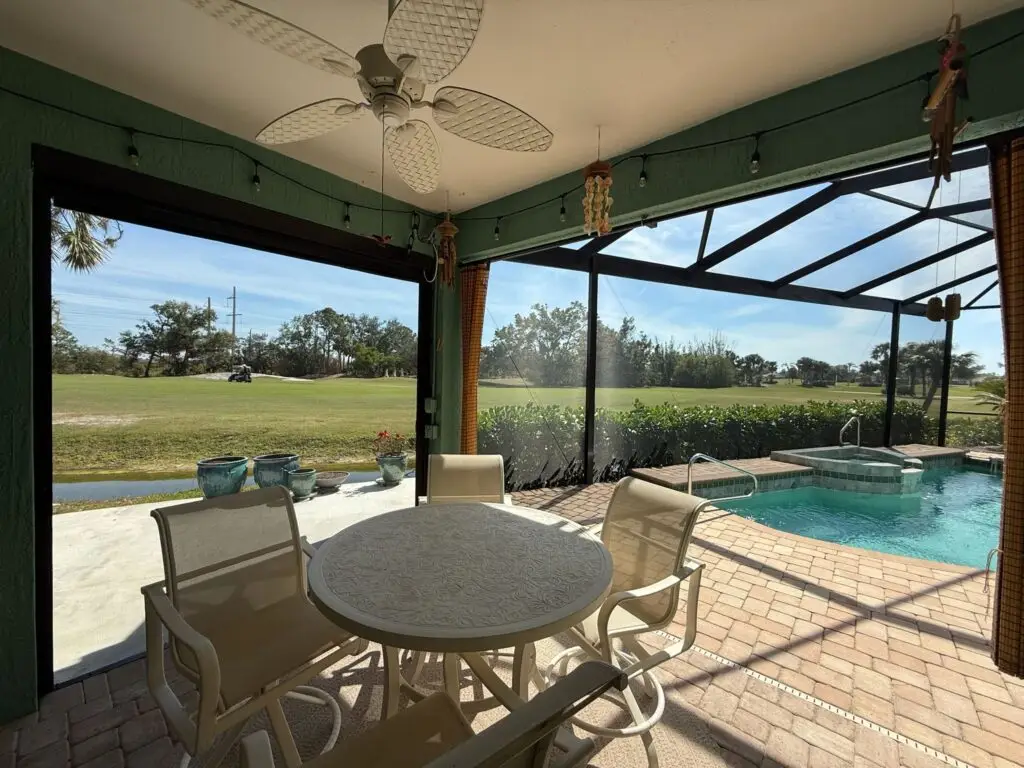 Screen enclosure with pool, patio seating, and ceiling fan